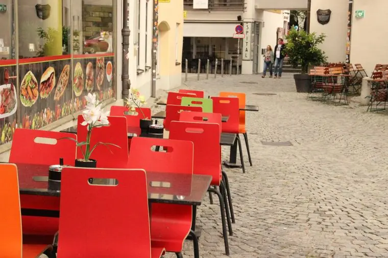Terrasse mit roten Stühlen in der Altstadtgasse