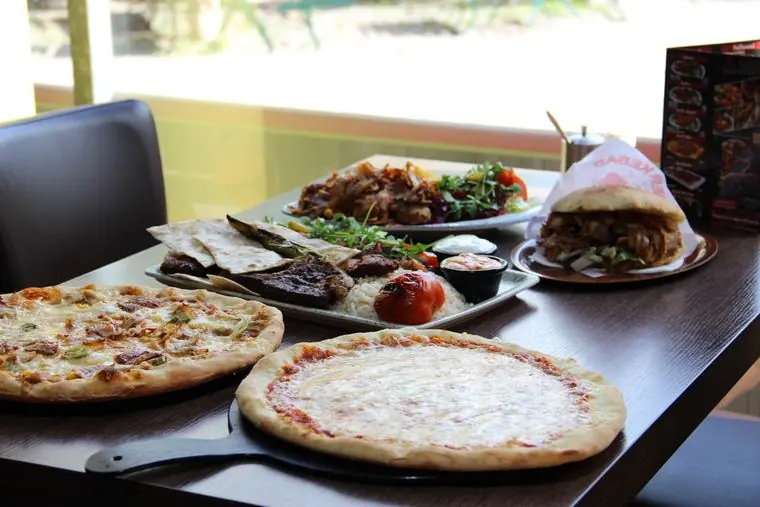 Döner, Grillteller und zwei Pizzen auf einem Tisch