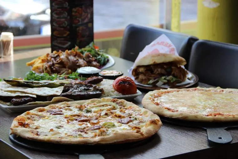 Döner, Grillteller und zwei Pizzen auf einem Tisch